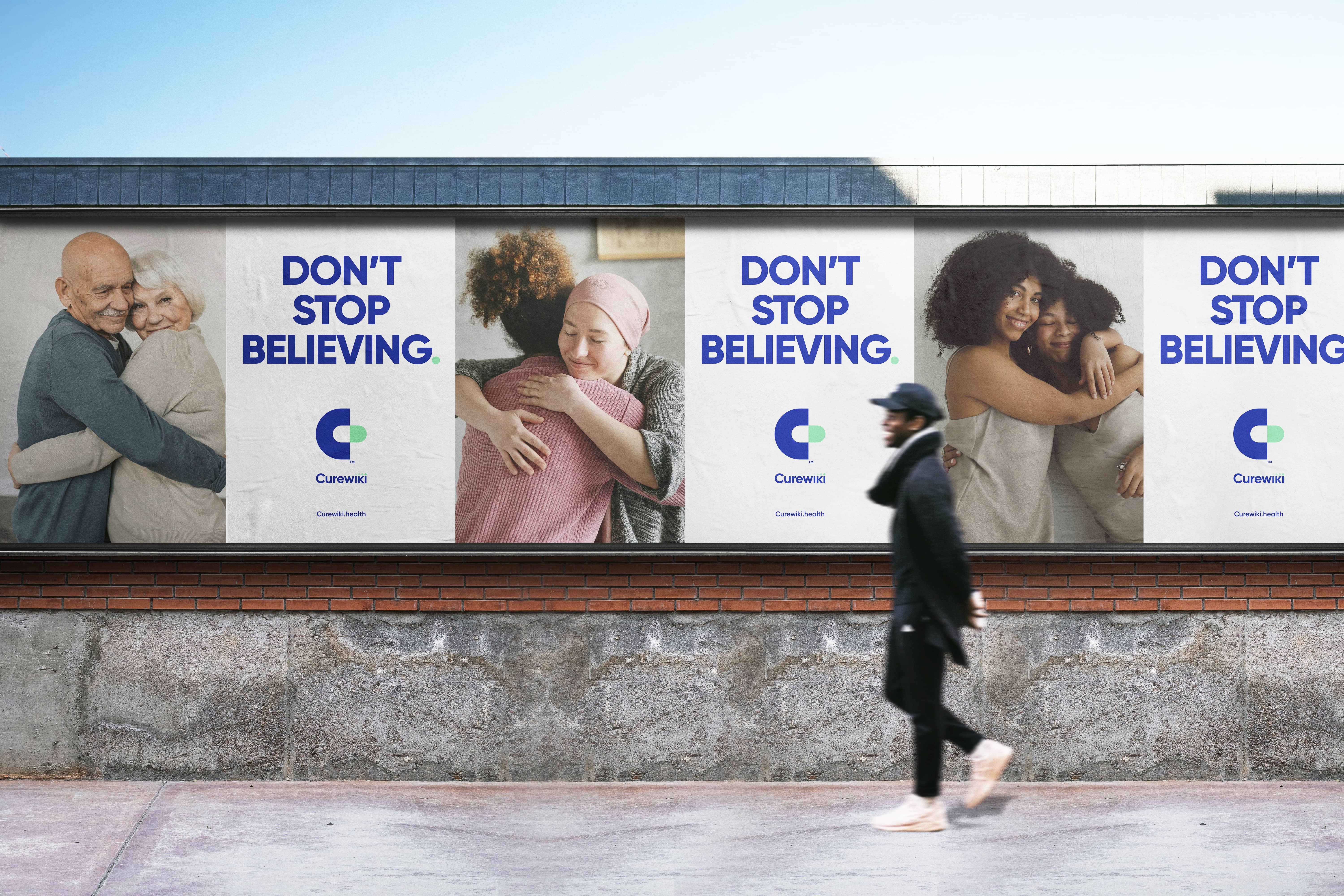 Person walking passed posters of Curewiki with the headline "Don't stop believing."