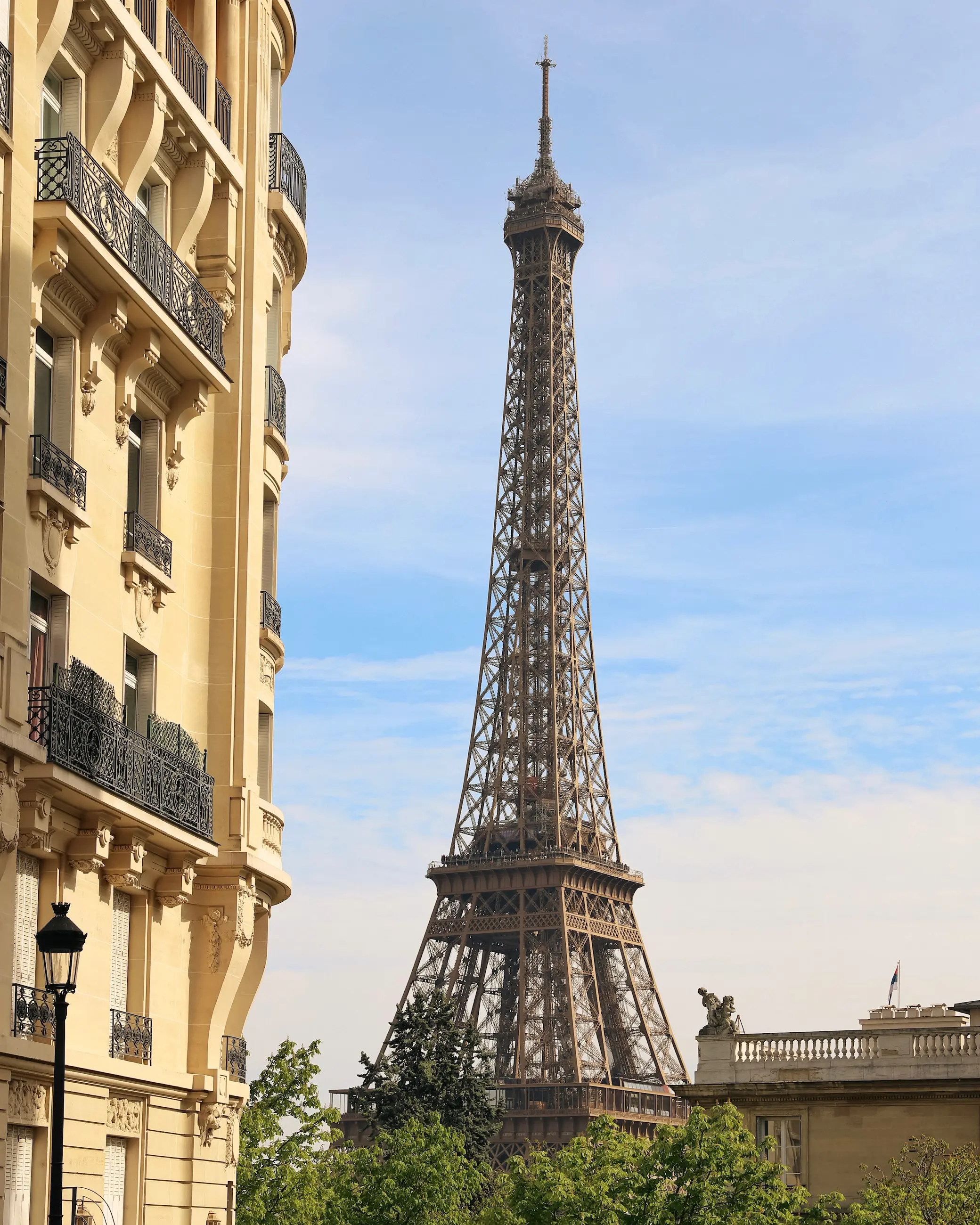 Eiffel Tower viewed from Avenue de Camoens in Paris framed by classic Haussmann buildings on a sunny spring day.