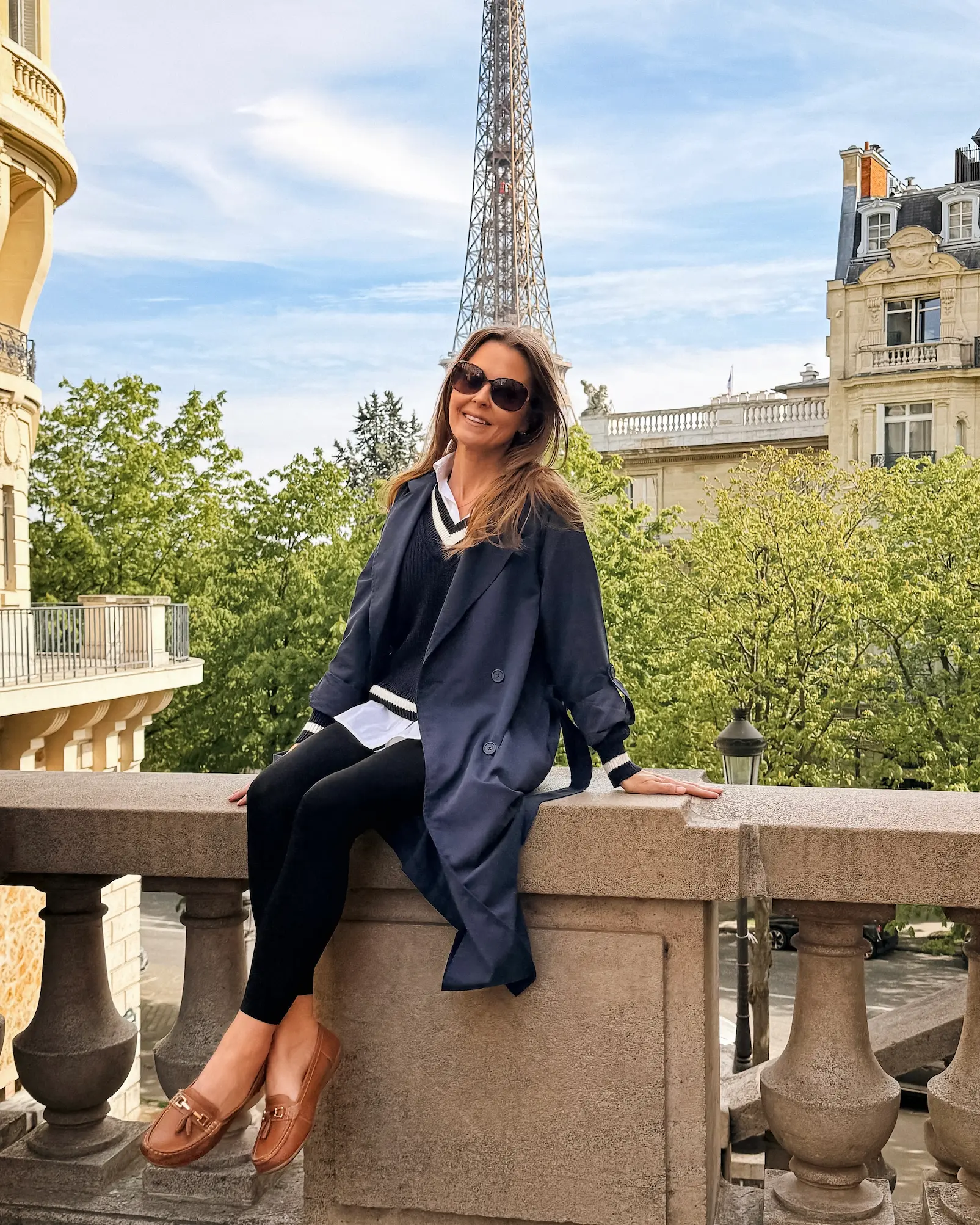 Woman posing with the Eiffel Tower in the background on Avenue de Camoëns in Paris on a sunny spring day.