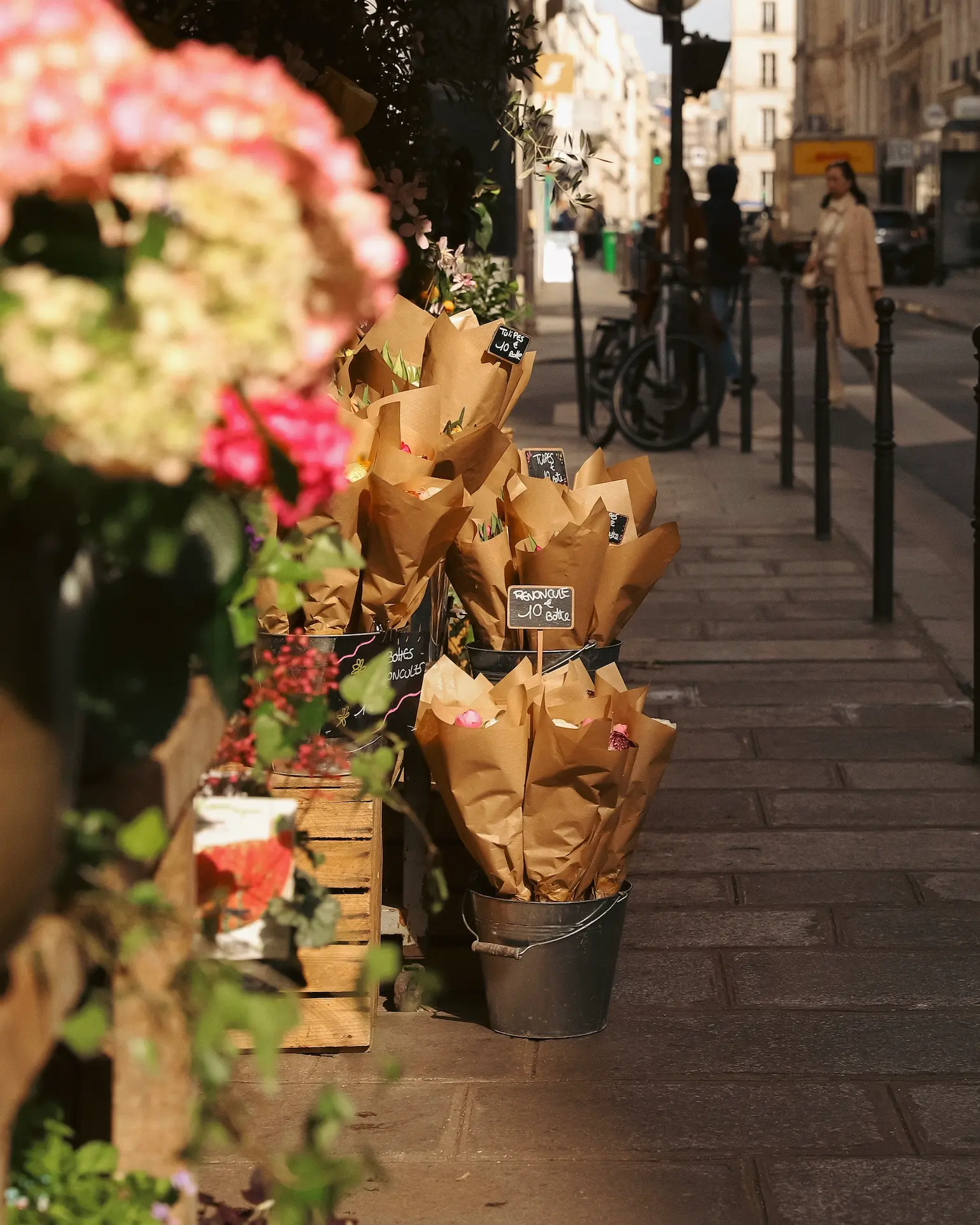 Flower shop display with wrapped bouquets outside on a Paris street in warm spring sunshine.