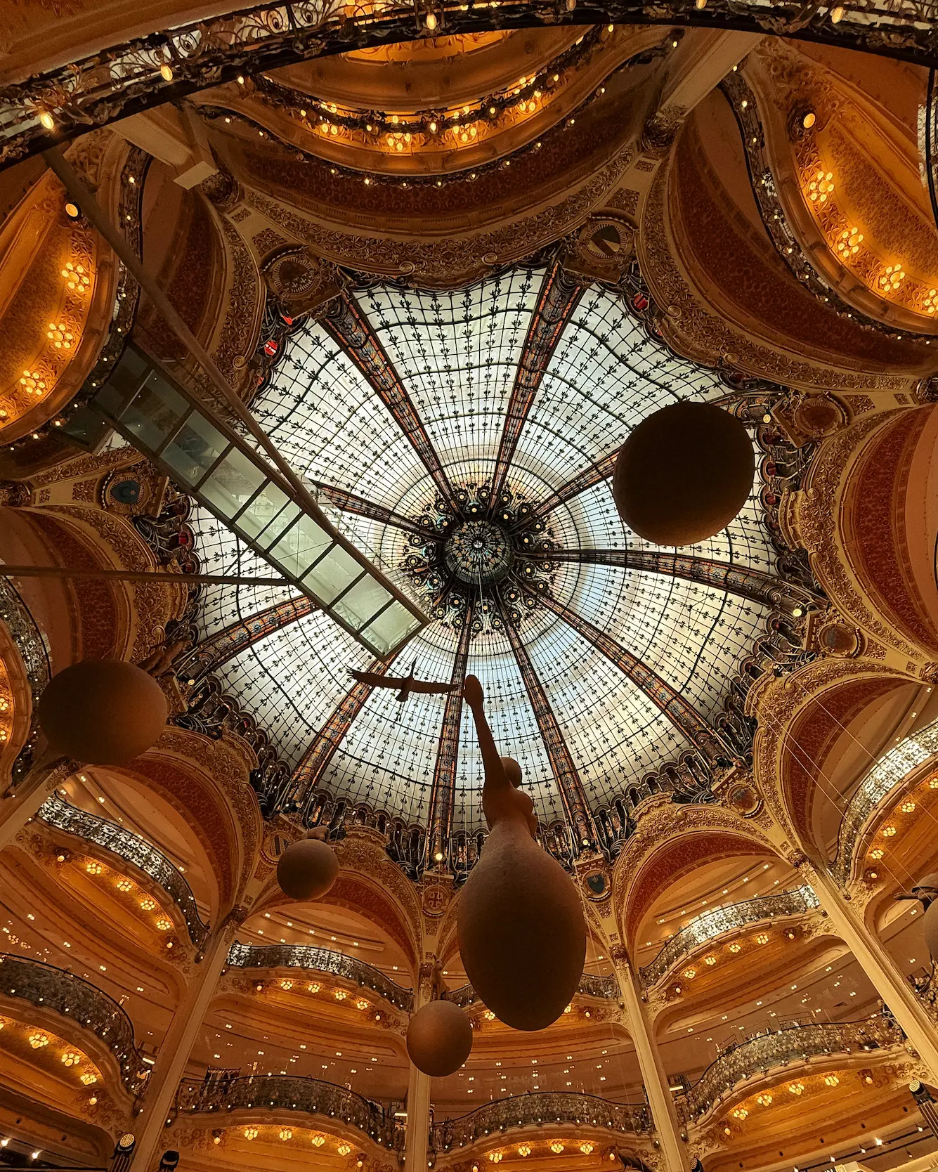 Ornate glass dome ceiling inside Galeries Lafayette Haussmann department store in Paris.
