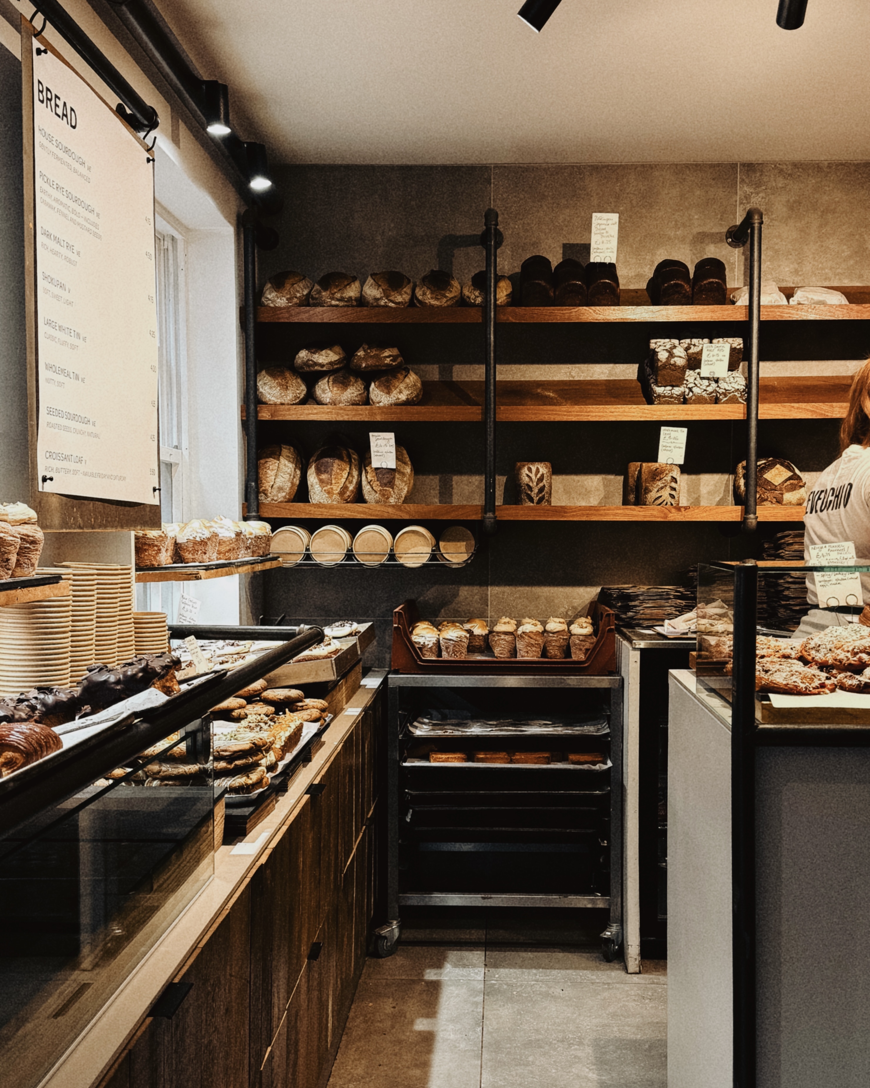 Interior of Devecchio bakery in Norwich with shelves of artisan sourdough loaves, pastries and a warm, modern bakery space