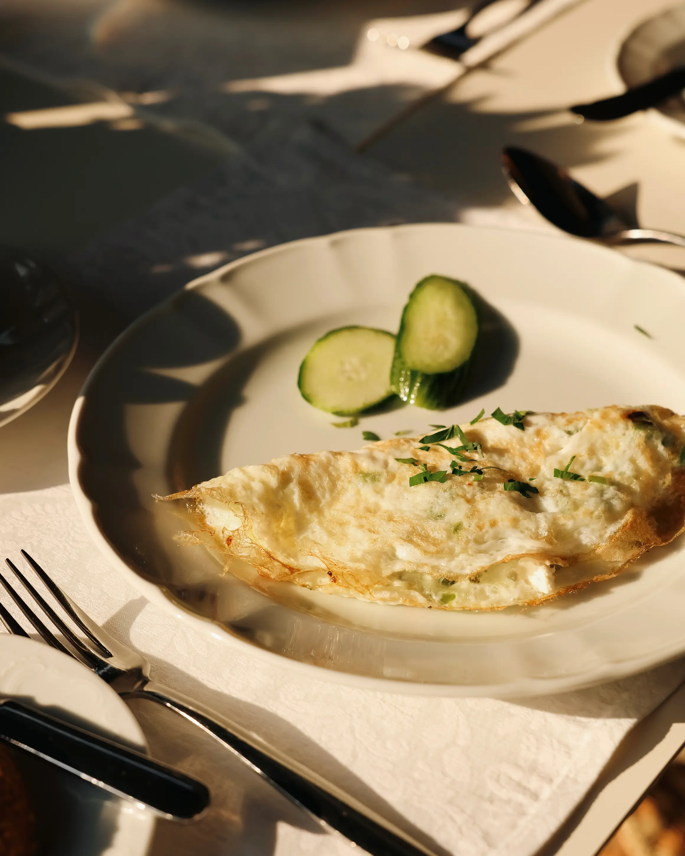 Freshly cooked omelette served for breakfast at Rodos Park in Rhodes, with cucumber and herbs in the morning light.