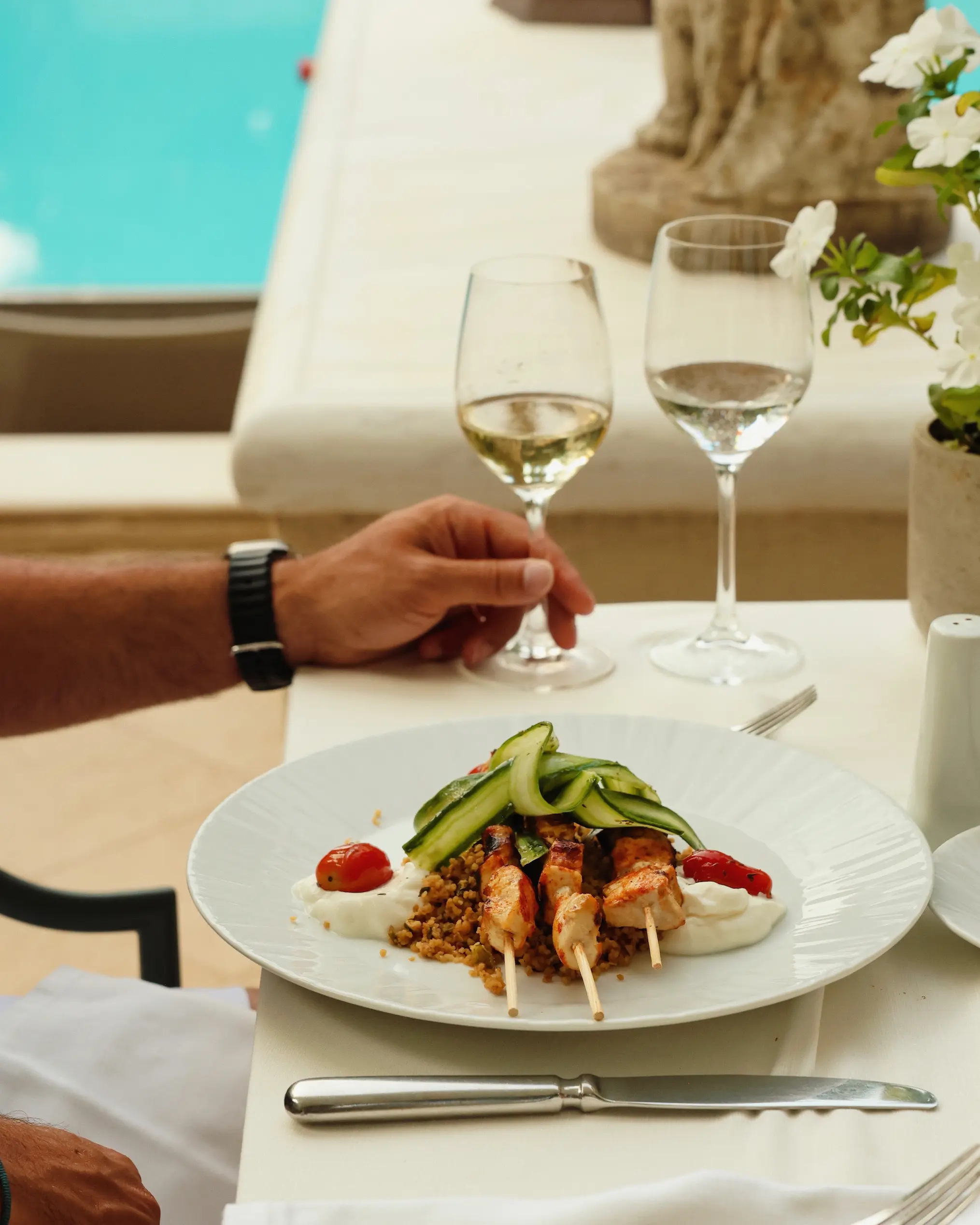 Chicken skewers served with grains, yoghurt, cucumber ribbons and roasted tomatoes beside the pool at Rodos Park in Rhodes.