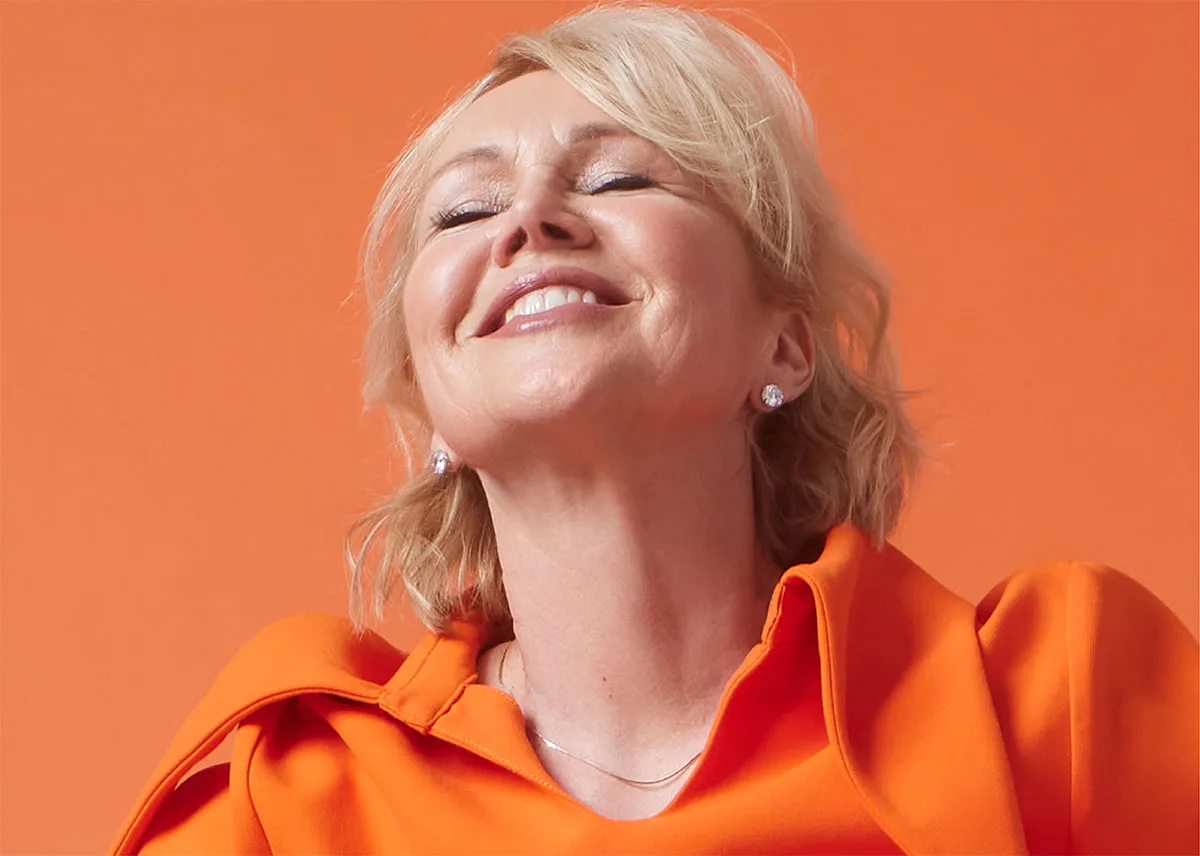 Portrait of singer and pianist Anne Bisson against an orange background