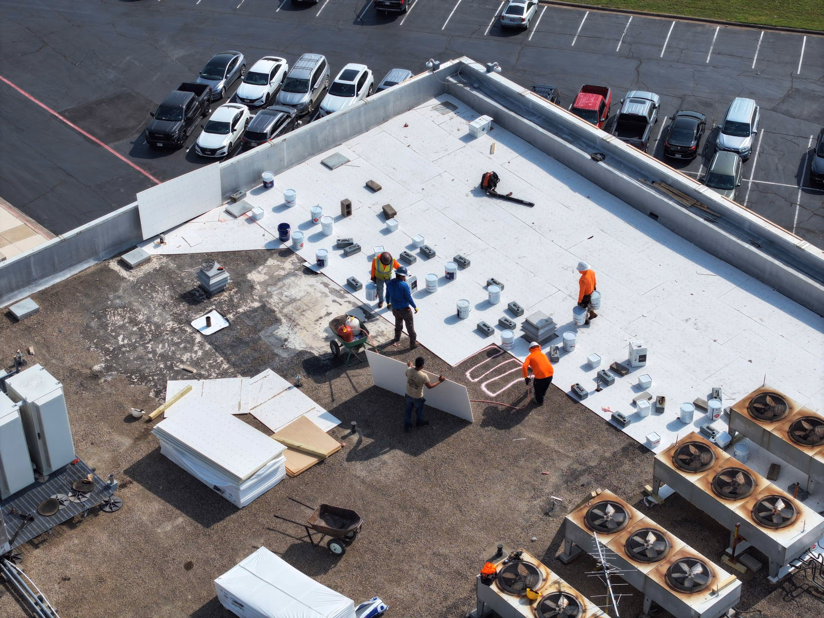 Roofing crew replacing a commercial roof around rooftop HVAC units.