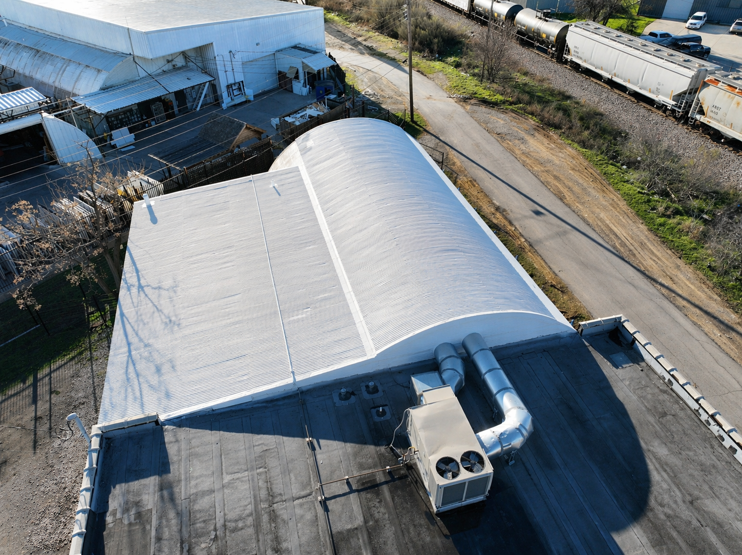 Curved metal commercial roof with a white protective coating.