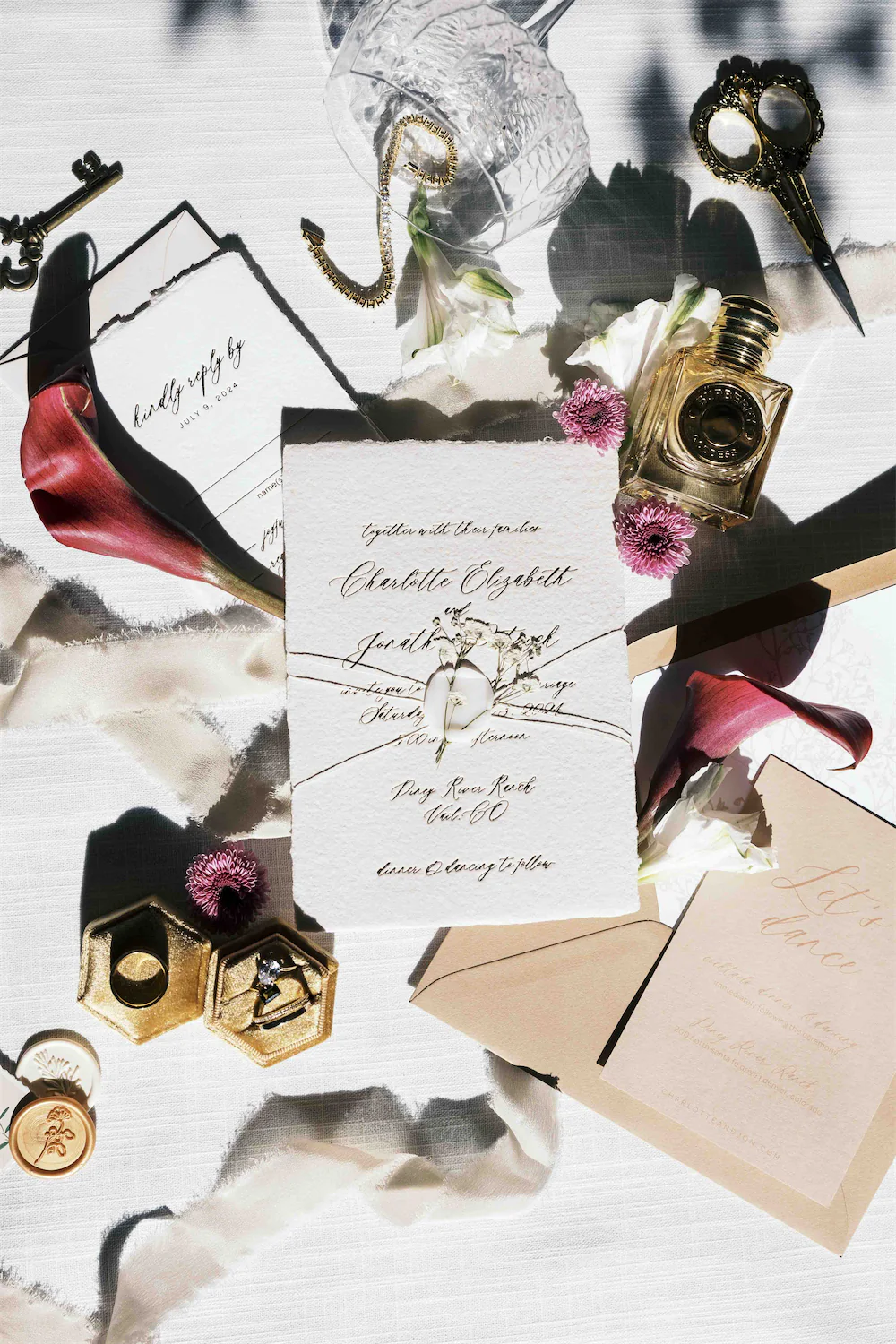flat lay detail photo featuring light and shadows, calla lilllies, jewelry, and an elegant invitation suite 