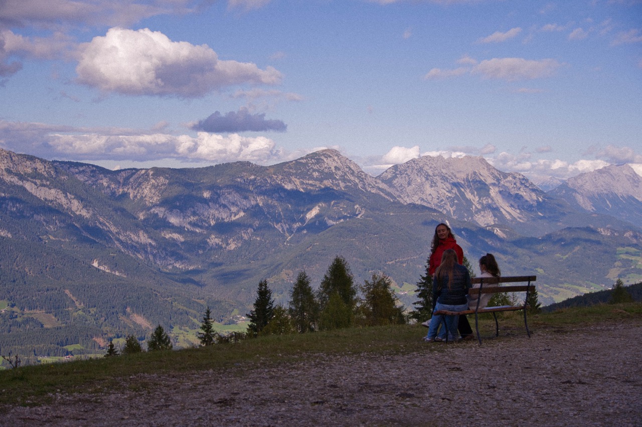 Idyllischer Panorama-Ausblick in den Bergen. GrowDeep junge Erwachsene sitzen auf einer Bank und genießen den Ausblick