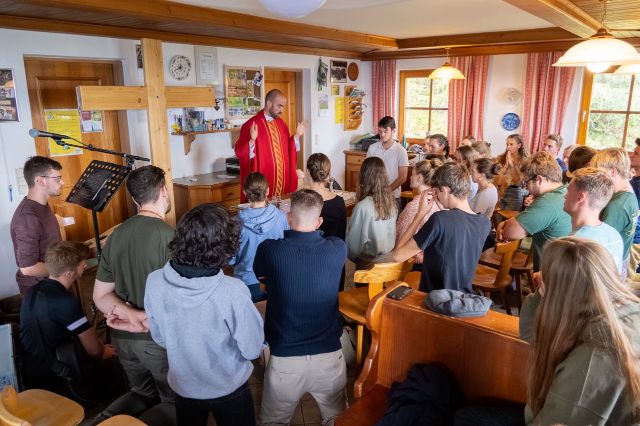 Jungedliche feiern die Heilige Messe in einer Hütte mit Pater Andrew im Priestergewand