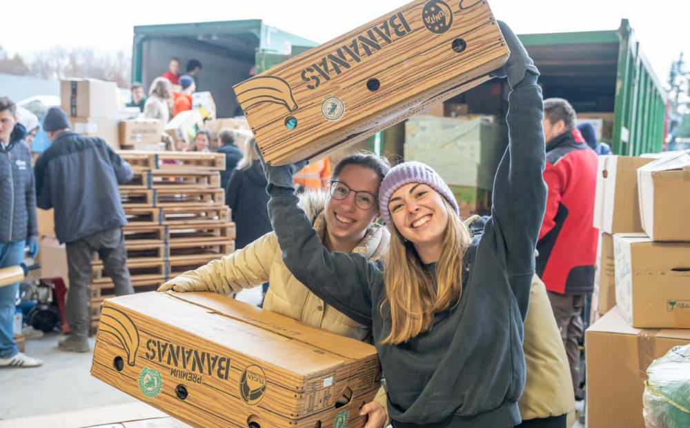 Freiwillige heben leere Obstkisten in die Höhe und packen Spenden ein beim Grow Deep Wochenende