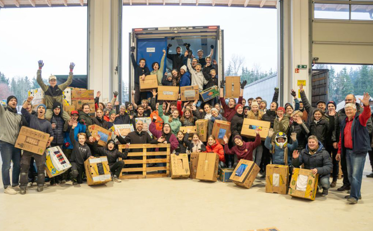 Gruppenfoto der Aktion „Junge Leute helfen“ in Großbergham mit vielen jungen Erwachsenen, die gepackte Hilfspakete vor einem Lkw halten.