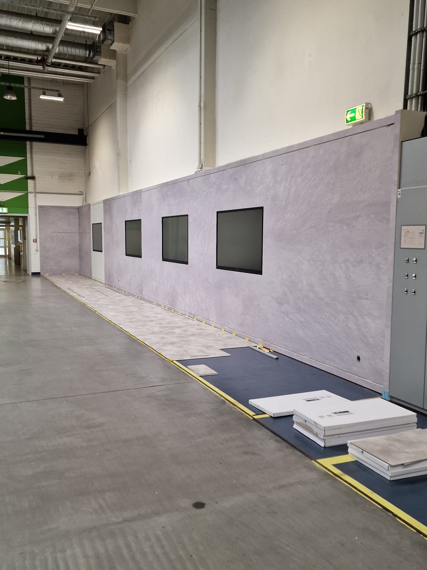 Wand in Betonoptik mit montierten Monitoren vor der Grafik