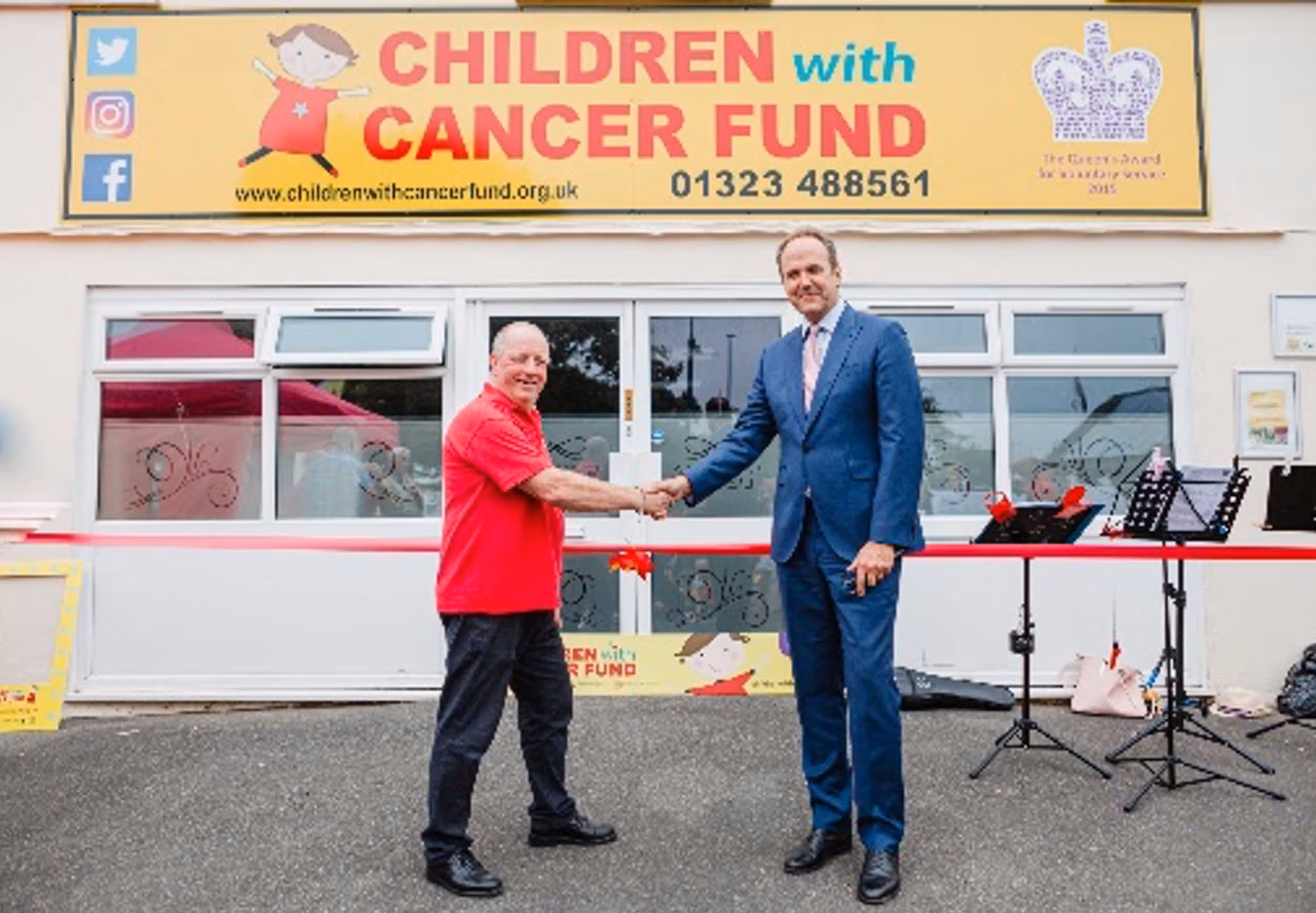 Two men shaking hands in front of the children's cancer fund building.
