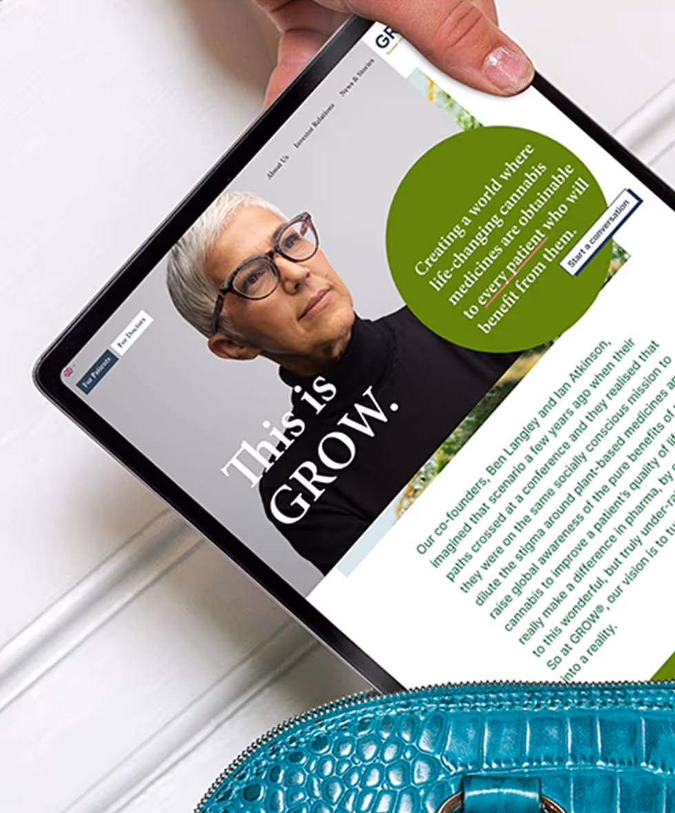 iPad showing GROW Group homepage and teal handbag