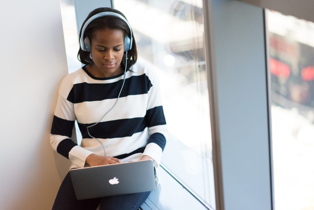 Woman working by a window with headphones on.