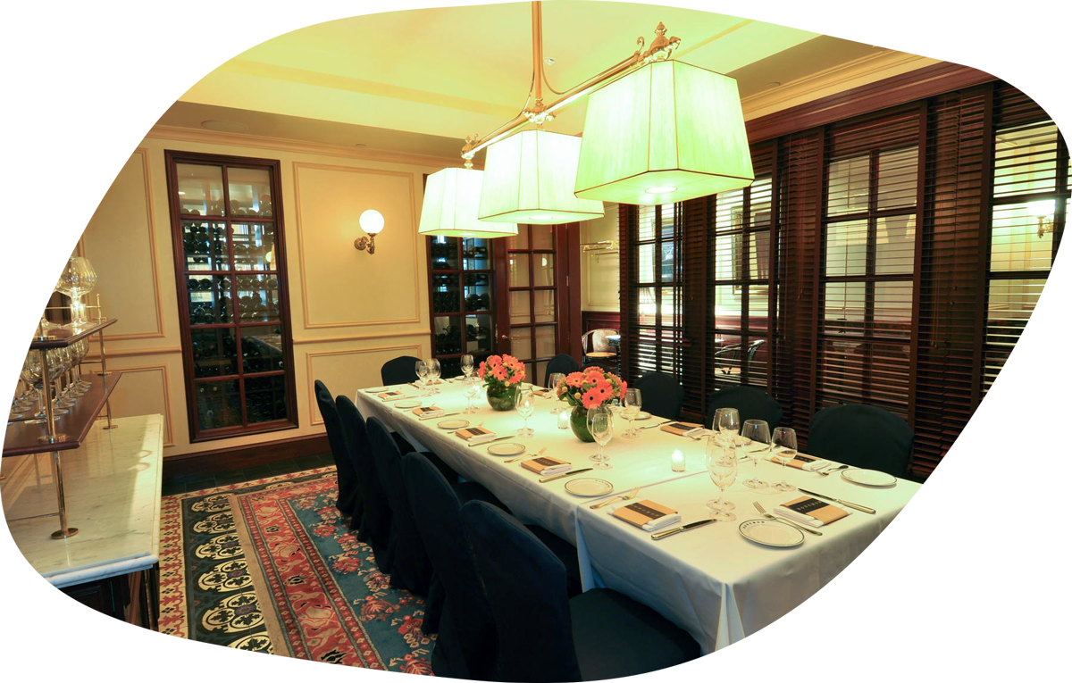 Elegant dining room with a long table, white tablecloth, floral centerpieces, and dark chairs.