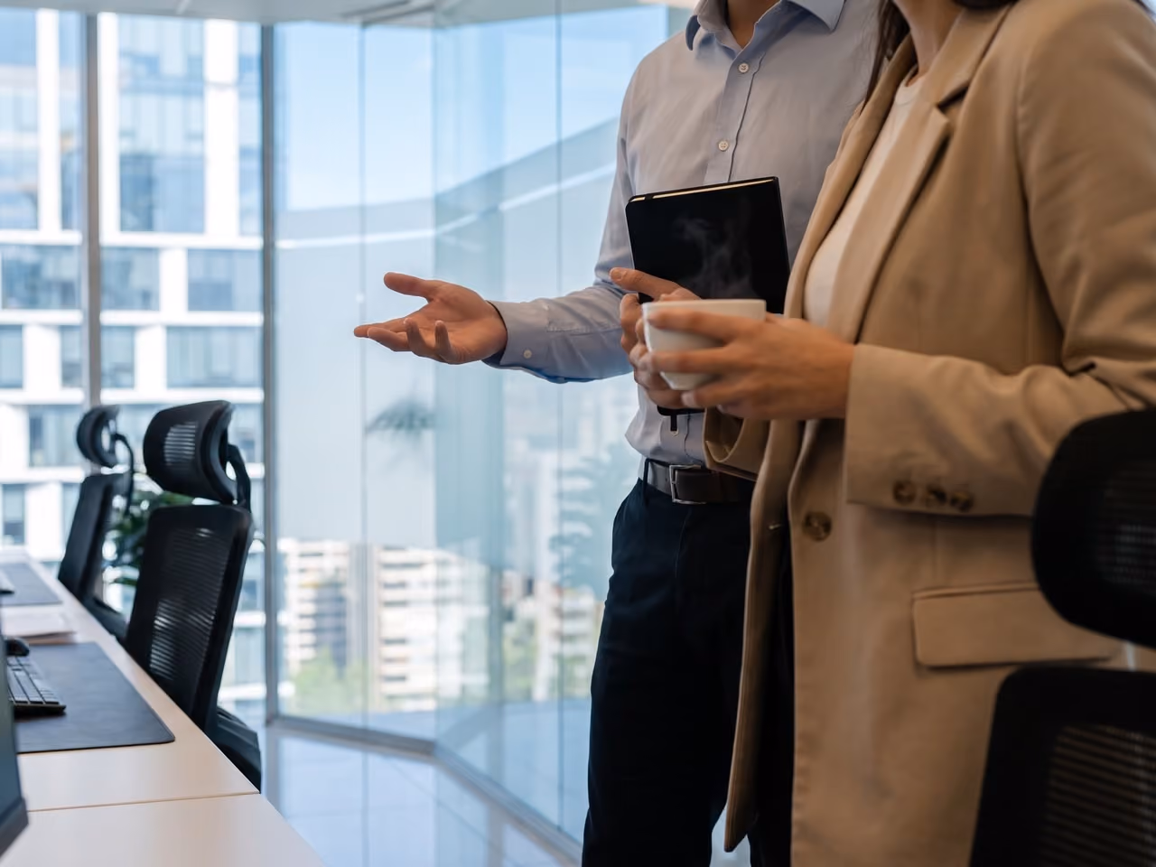 Dos personas conversando en una oficina con vista a Las Condes