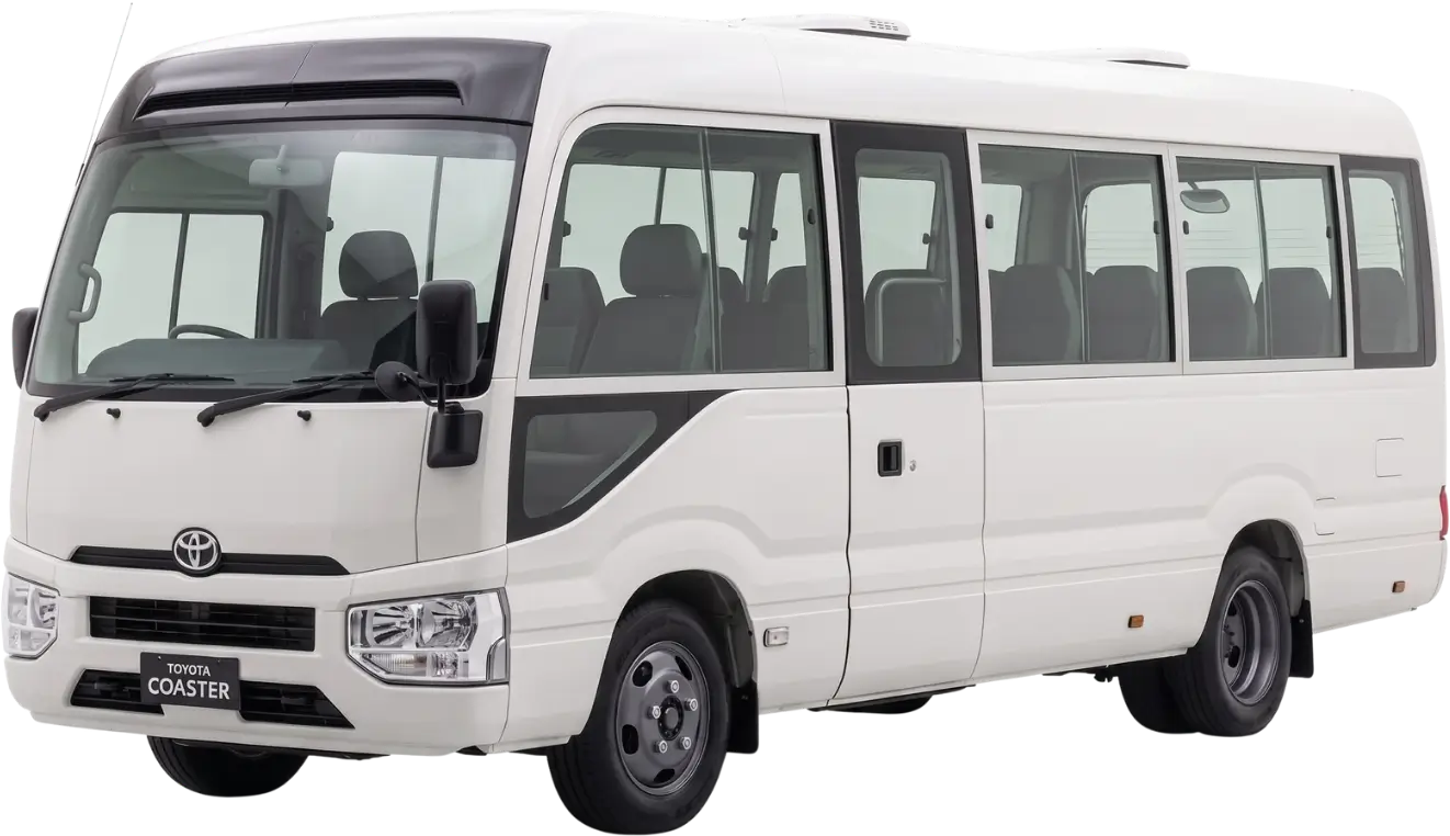White Toyota Coaster minibus with tinted windows and black side mirrors viewed from front left side.
