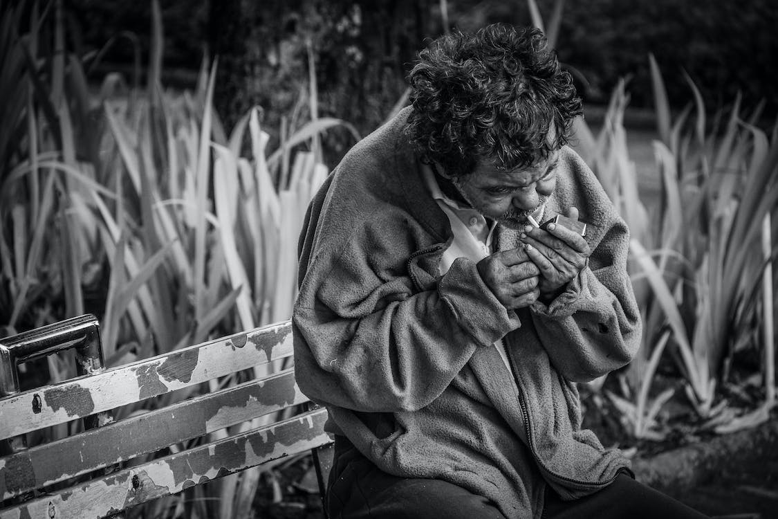 Free Grayscale Photo of Man With Cigarette Sitting on Bench Stock Photo