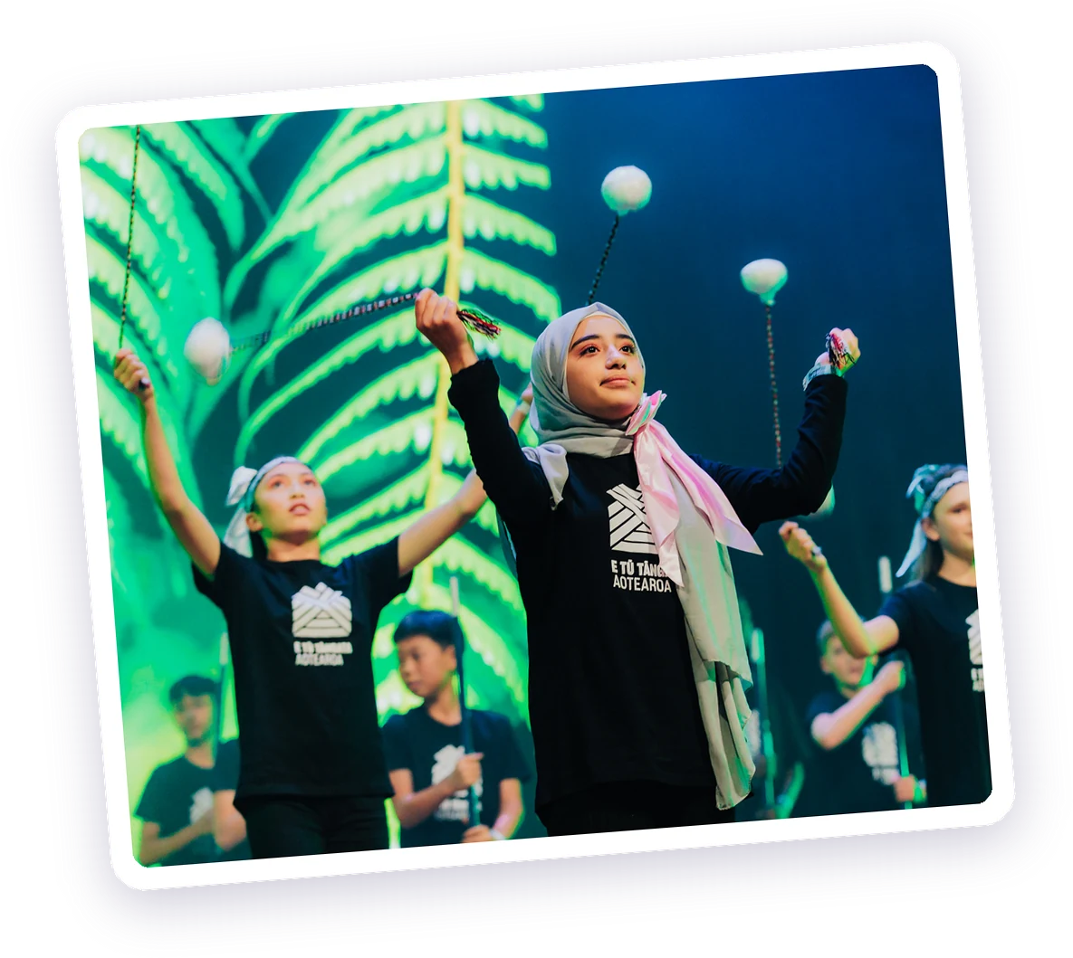 Rangatahi performing poi on stage in E Tū Tāngata Aotearoa t-shirts