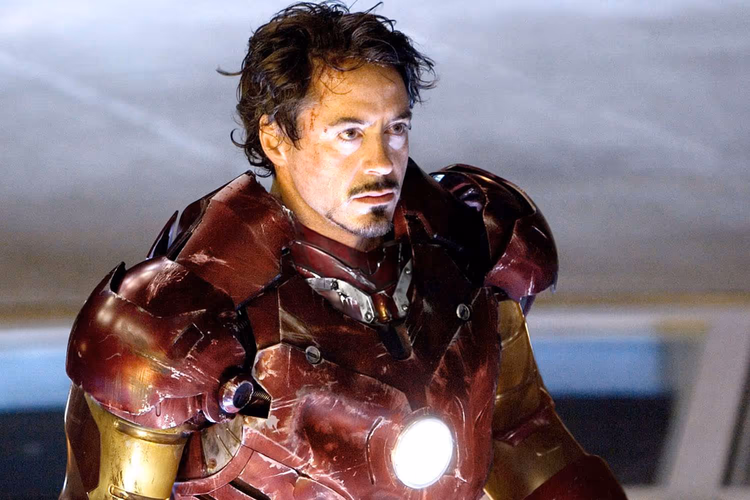 Tony Stark with Ironman suit, helmet off, beat up from a battle