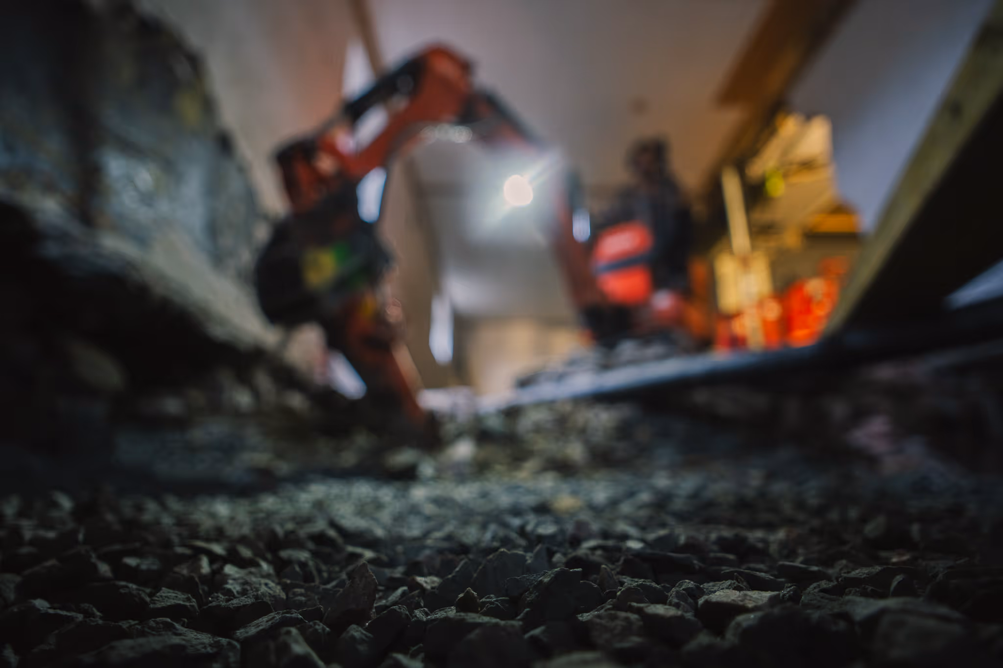 Gravemaskin i bakgrunn, grus i forgrunn.