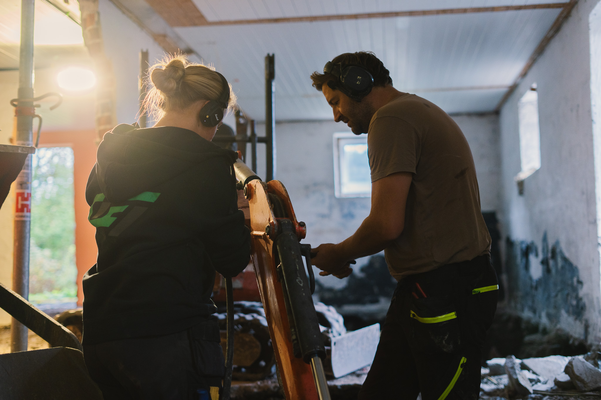 Bilde av ansatt som fører gravemaskin i kjeller for utgraving.