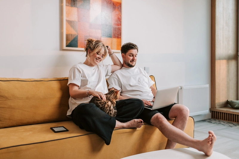 couple relaxing together on a yellow sofa with a laptop at home