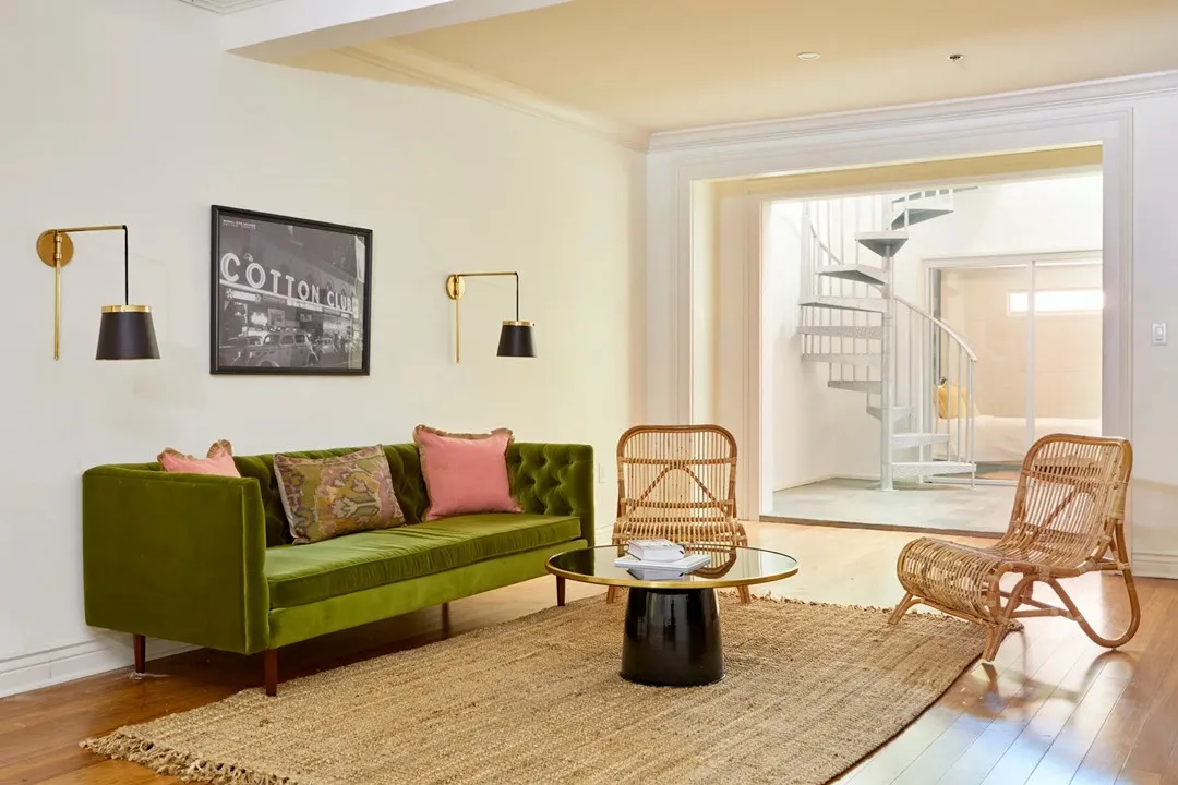 living room with green velvet sofa rattan chairs and spiral staircase in new orleans