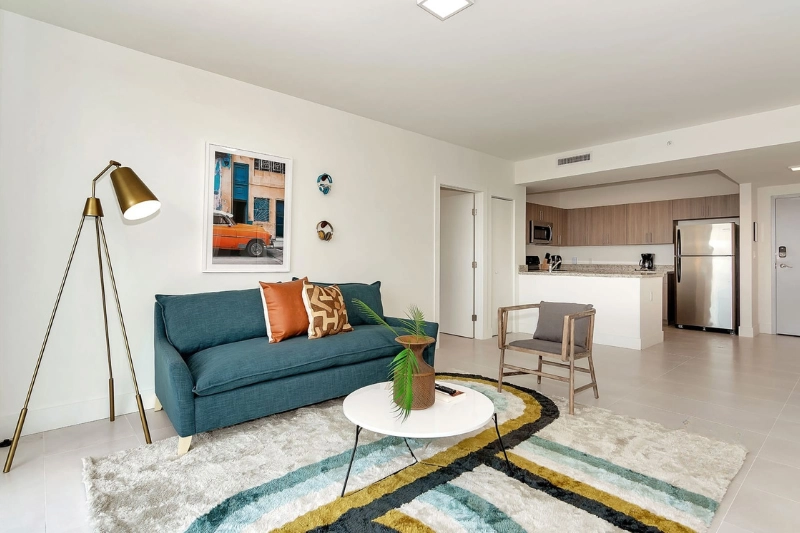 living room with teal sofa orange pillows and colorful rug at grove 27 by roami