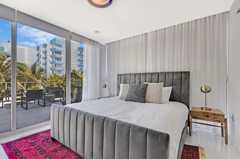 bedroom with grey velvet bed and balcony view at 250 collins by roami