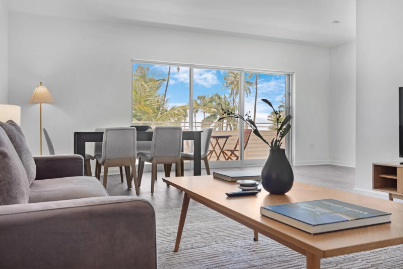 living and dining area with wooden coffee table and palm view windows at 1200 ocean by roami