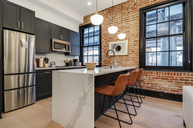 kitchen with marble island leather bar stools and brick wall at the lola by roami