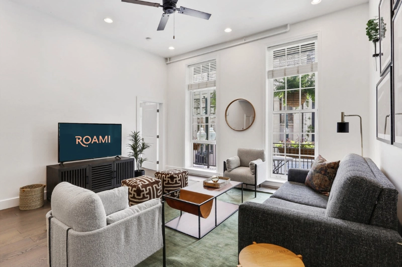 living room with ceiling fan tall windows and grey sofa at bourbon place by roami