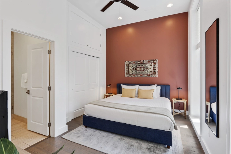 bedroom with terracotta accent wall navy bed and ceiling fan at bourbon place by roami