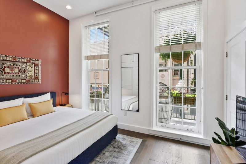 bedroom with red accent wall yellow pillows and tall windows at bourbon place by roami