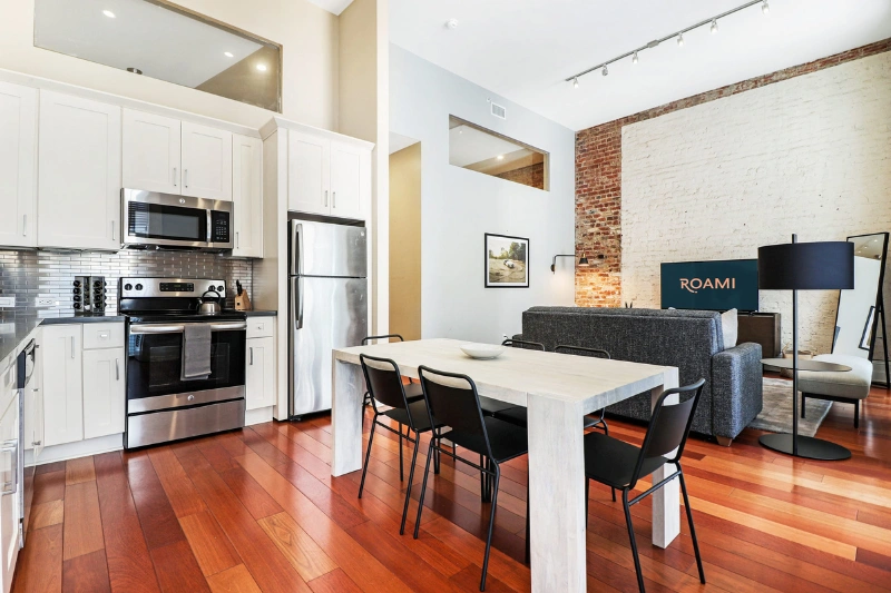 white kitchen and dining table with hardwood floors at factors row by roami