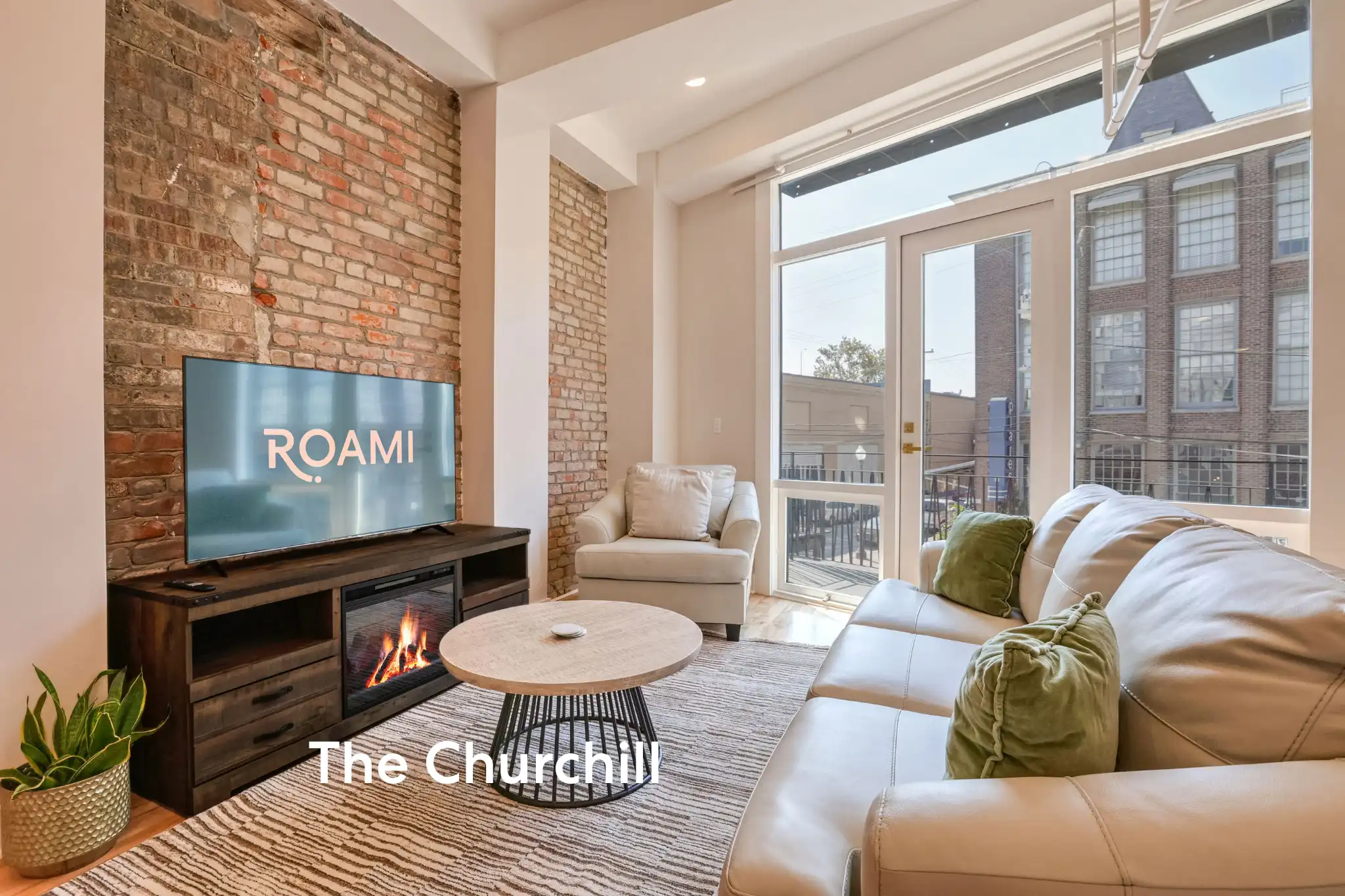 living room with brick wall fireplace and white sofa at the churchill by roami