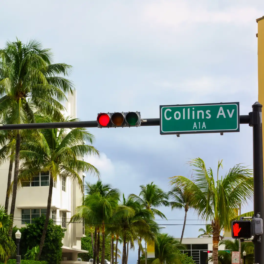 collins avenue street sign with traffic light and palm trees in miami beach