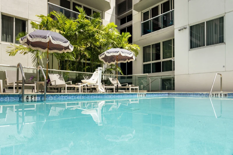 outdoor swimming pool with umbrellas lounge chairs and tropical plants