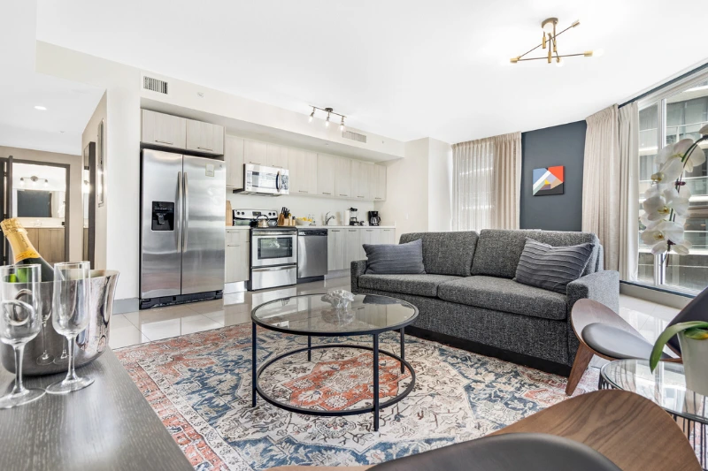 living room with grey sofa patterned rug and open kitchen