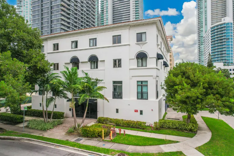 white low rise building with palm trees and lawn in miami
