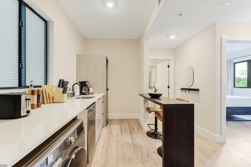 galley kitchen with white cabinets and breakfast bar leading to the bedroom
