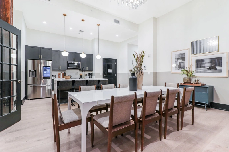 shared kitchen and long dining table with wooden chairs in a resident clubroom