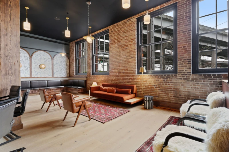 industrial style resident lounge with brick walls large windows and lounge chairs
