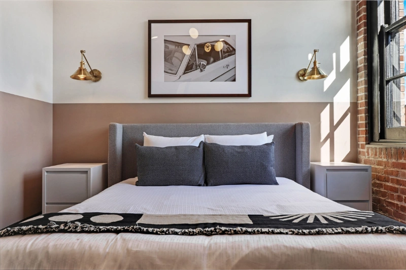 cozy bedroom with grey headboard brass wall lamps and framed art