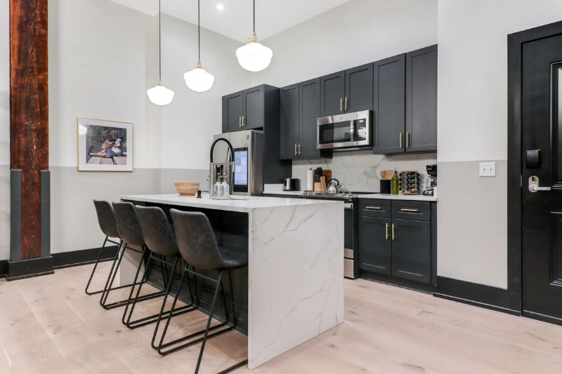 modern kitchen with dark cabinets pendant lights and island with bar stools