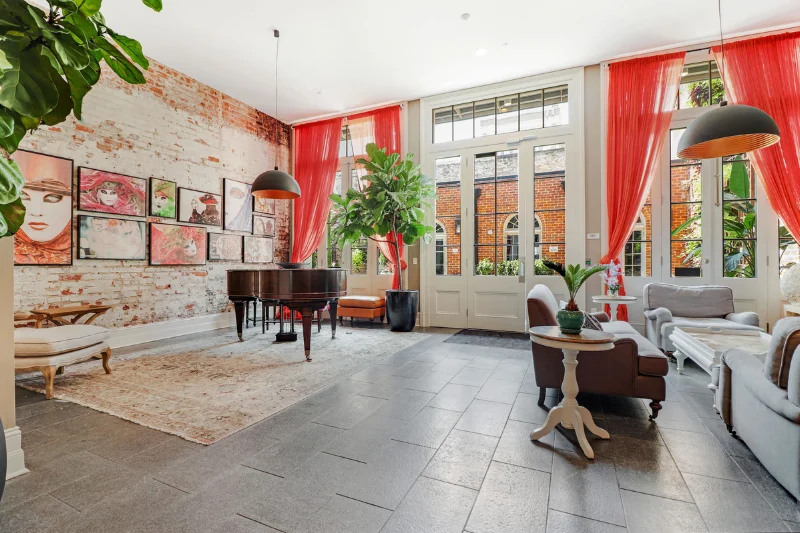 spacious lounge with red curtains piano and artwork on a brick wall