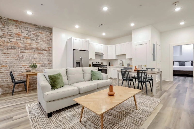 bright open plan living room with sofa brick wall and kitchen in a roami apartment